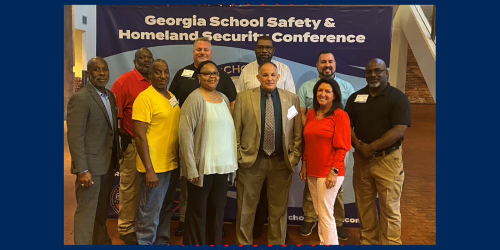 Group of administrators pose in front of sign reading "Georgia school safety and homeland security conference"